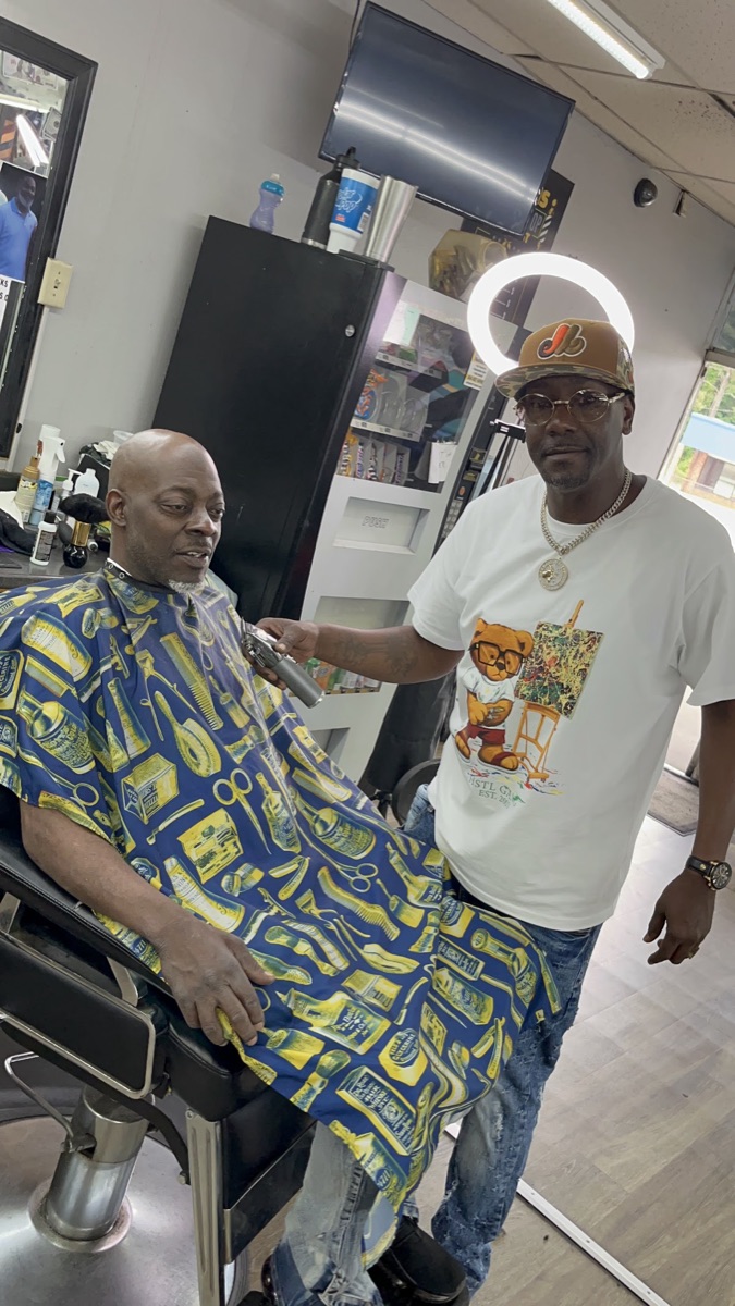 Inside Blend Addicts Barbershop — a barber lining up a client